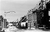 Een foto uit 1930 van de Dorpstraat met nog duidelijk zichtbaar de tramrails en de daarnaast lopende beek de Oir. In het wittehuisje (tweede van rechts) woonde 'An va Kate' zoals men haar in de volksmond noemde. Op de achtergrond zien we de school, waar toen op de zolderverdieping het gemeentehuis was gevestigd.