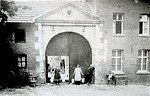 Kasteelboerderij, vroeger behorende bij het Doonder Huuske. Kasteel en boerderij zijn Rijksmonumenten. De familie Jeurissen beheert de boerderij al generaties lang. Links van de poort de wasmachine en een slijpsteen.
V.l.n.r. Lucia en Lena Jeurissen met juk of puthaam, Zef Jeurissen en zittend op de bank Pierre Jeurissen.