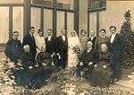 Foto gemaakt tijdens het kerkelijk huwelijk van A.J. Gerard Fleischeuer en Philomena Catharina Bettonville op 7 augustus 1923 in Oirsbeek. Het huwelijk werd ingezegend door pastoor Wilhelmus Jacobus Krijns.
Op de foto staand v.l.n.r.: Johannes Röselaars die van 1921 tot 1924 kapelaan in Oirsbeek was, Jan Petrus Karel Gabrils, burgemeester van Oirsbeek, Eugenie Ackermans (gehuwd met Hubert Kusters), Guillaume Bettonville (ongebuwde broer van de bruid), Gerard Adle jan Fleischeuer (bruidegom), Philomena Catharina Bettonville (bruid), Onbekend, maria Hubertina Jacqueline Cremers - Fleischeuer (zus van bruidegom), Petrus Leonardus Hubert (Leo) Cremers (huwelijks getuige en zwager van bruidegom) Burgemeester van Nuth. Zittend v.l.n.r.: Wilhelmus jacobus Krijns (Pastoor van Oirsbeek van 1922-1926), Flicitas Fleischeuer - America, (moeder vab bruidegom), Frans Lambert Willebrordus Fleischeuer (vader bruidegom) Anna Meulenberg (verm. dienstmeid).
De foto is genomen achter de serre van het huis gelegen in de Dorpstraat te Oirsbeek.